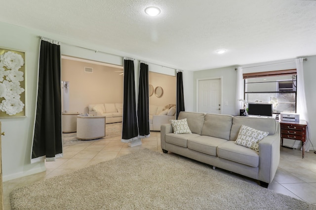 living room with a textured ceiling and light tile patterned flooring