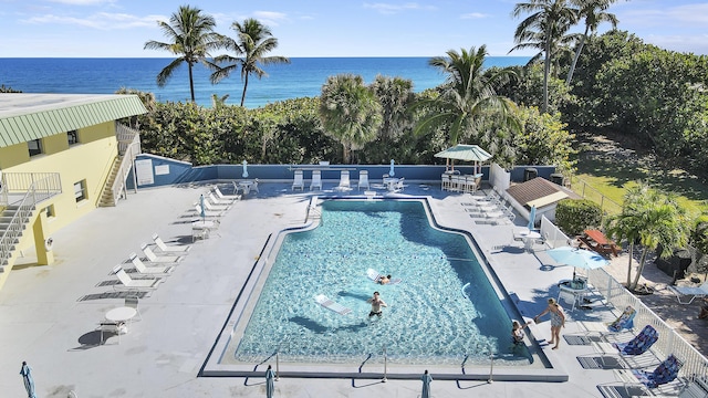 view of pool featuring a water view and a patio