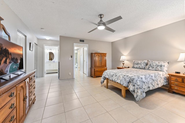 bedroom featuring ensuite bathroom, ceiling fan, light tile patterned floors, and a textured ceiling