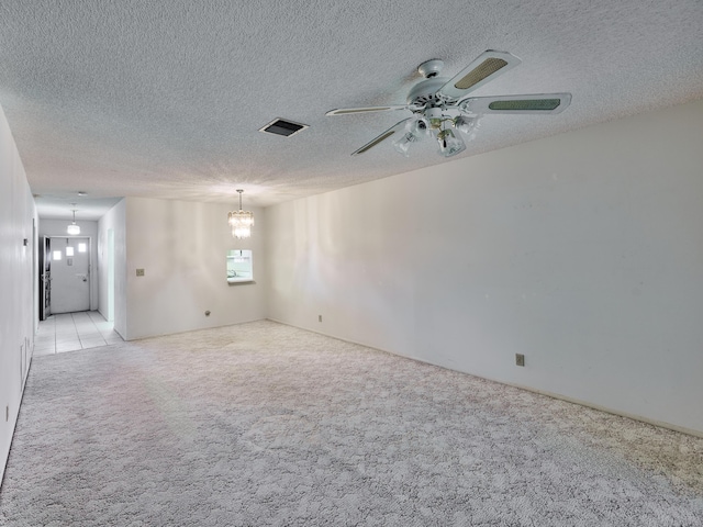 carpeted empty room with ceiling fan with notable chandelier and a textured ceiling