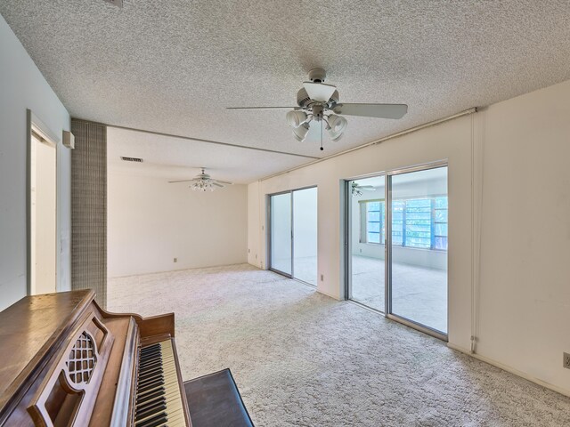 unfurnished living room featuring a textured ceiling, light colored carpet, and ceiling fan