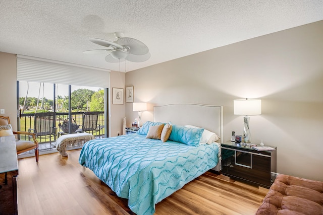 bedroom with access to exterior, ceiling fan, wood-type flooring, and a textured ceiling