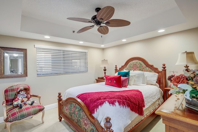 carpeted bedroom with a raised ceiling and ceiling fan