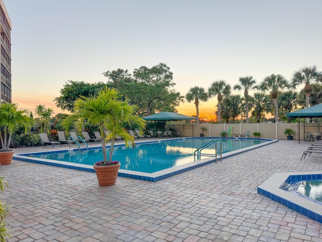 pool at dusk featuring a patio