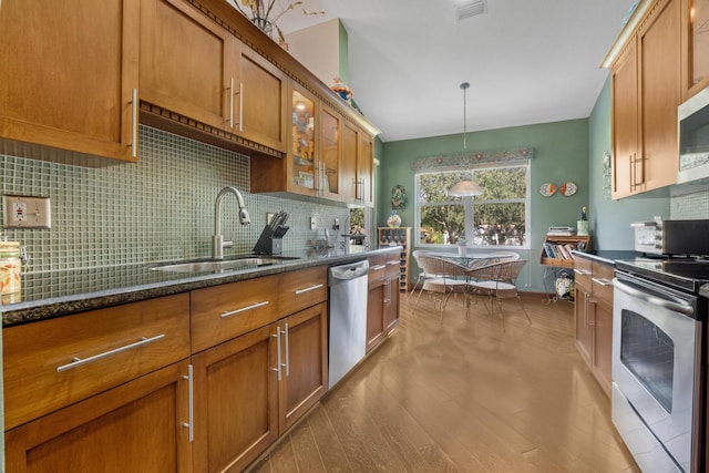 kitchen with sink, tasteful backsplash, decorative light fixtures, dark stone counters, and stainless steel appliances