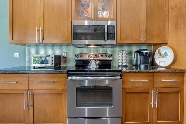 kitchen featuring appliances with stainless steel finishes, dark stone countertops, and backsplash