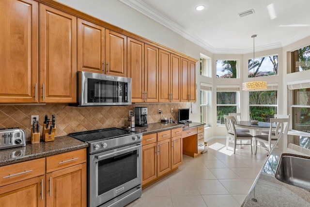 kitchen featuring a wealth of natural light, dark stone counters, decorative light fixtures, and appliances with stainless steel finishes