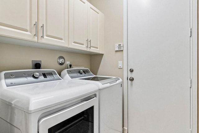 laundry room featuring separate washer and dryer and cabinets