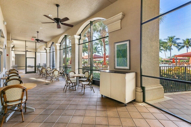 sunroom with decorative columns and ceiling fan