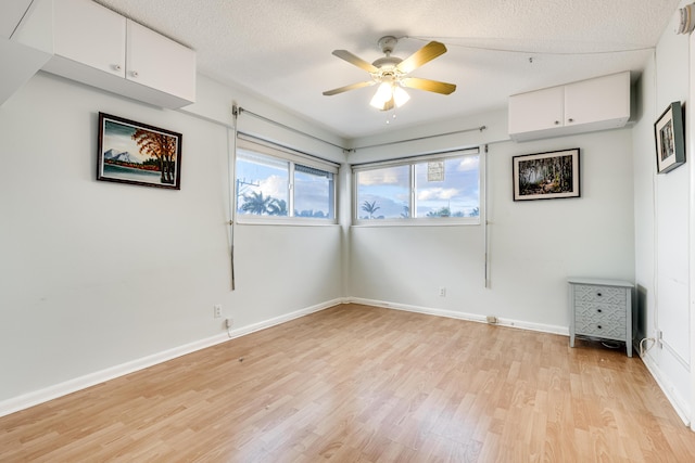 unfurnished room featuring a textured ceiling, light wood-type flooring, an AC wall unit, and ceiling fan