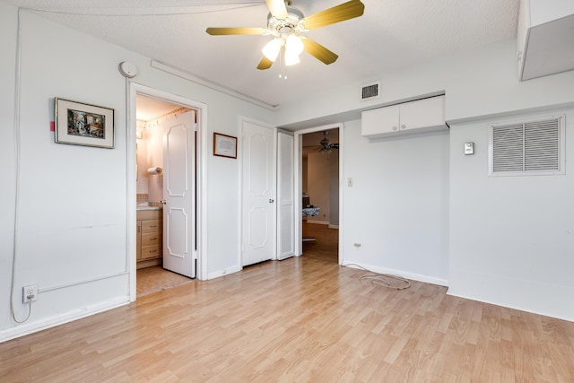 unfurnished bedroom featuring a textured ceiling, ensuite bathroom, light hardwood / wood-style flooring, and ceiling fan