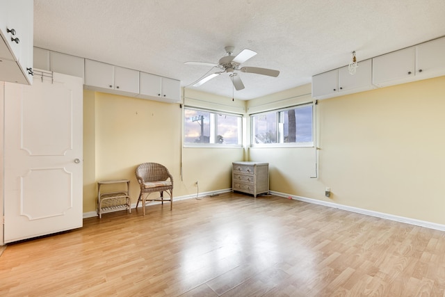 interior space with ceiling fan, light wood-type flooring, and a textured ceiling