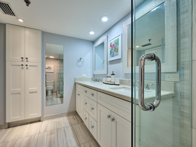 bathroom with vanity, a shower with shower door, and toilet