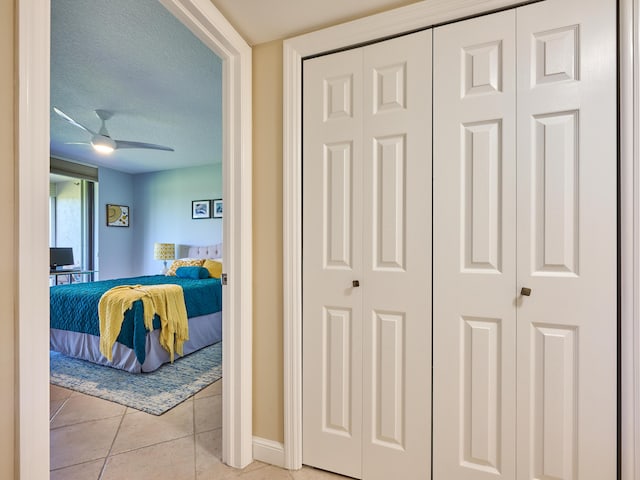 tiled bedroom with a textured ceiling and ceiling fan