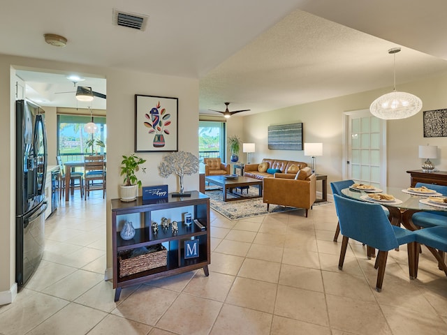 tiled living room featuring ceiling fan with notable chandelier and a textured ceiling