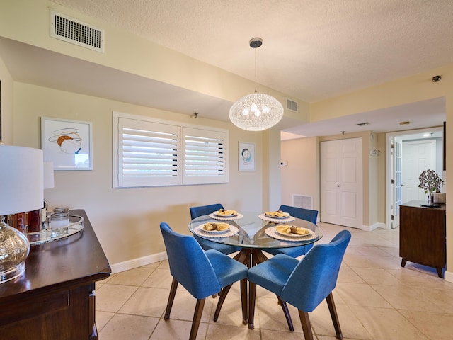 tiled dining area with a textured ceiling and a chandelier