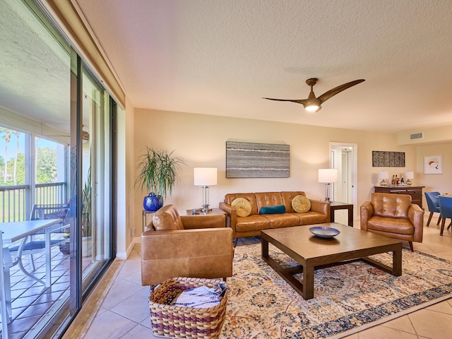 living room featuring light tile patterned floors, a textured ceiling, and ceiling fan