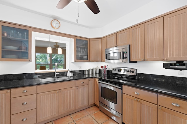 kitchen with dark stone counters, hanging light fixtures, sink, light tile patterned floors, and appliances with stainless steel finishes