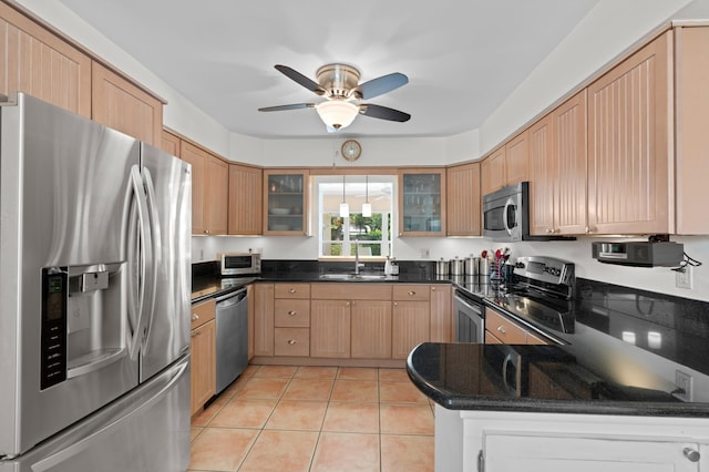 kitchen featuring appliances with stainless steel finishes, dark stone counters, ceiling fan, sink, and light tile patterned floors