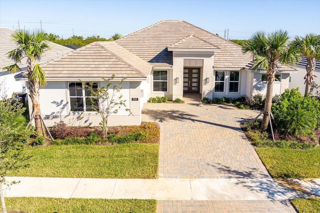 view of front of home featuring french doors, decorative driveway, a tile roof, and stucco siding