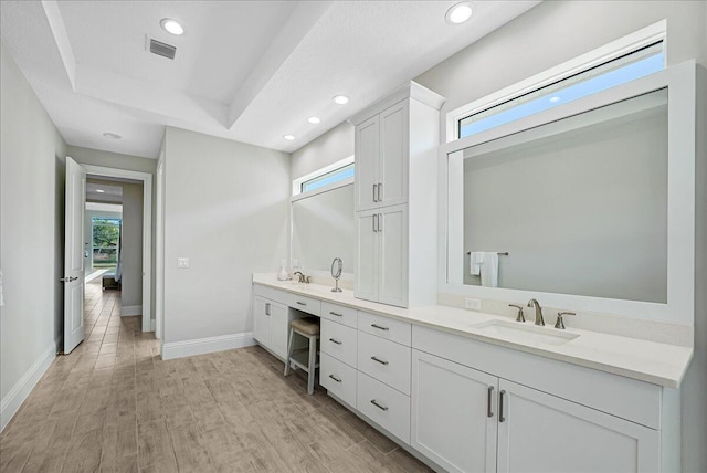 full bath featuring visible vents, baseboards, double vanity, wood finished floors, and a sink