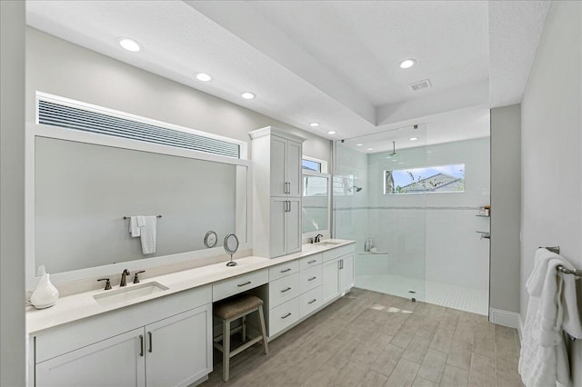 full bath featuring double vanity, visible vents, walk in shower, and a sink