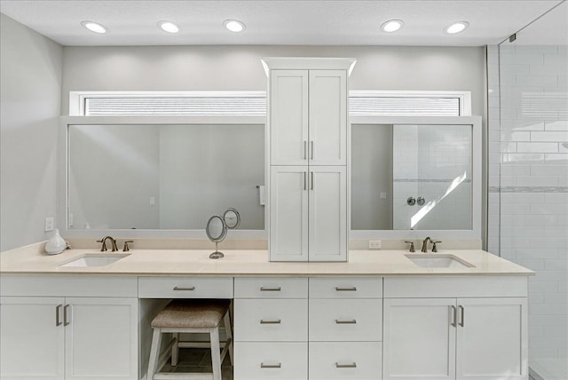 full bathroom with a sink, recessed lighting, double vanity, and a tile shower