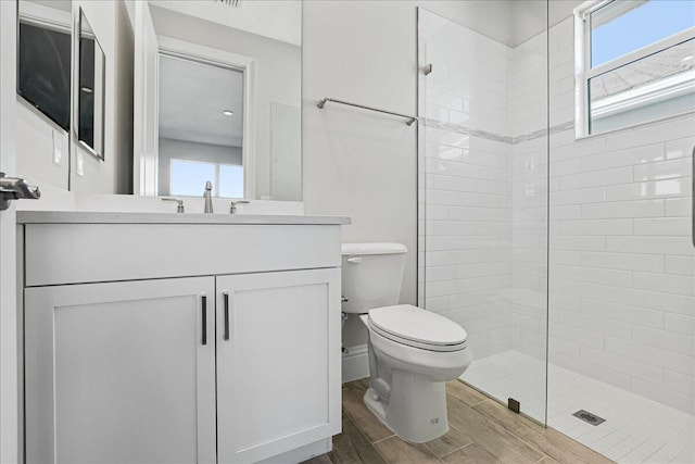 full bathroom with wood tiled floor, toilet, vanity, and a tile shower