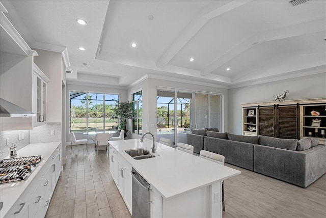 kitchen with open floor plan, stainless steel appliances, light wood-type flooring, and a sink