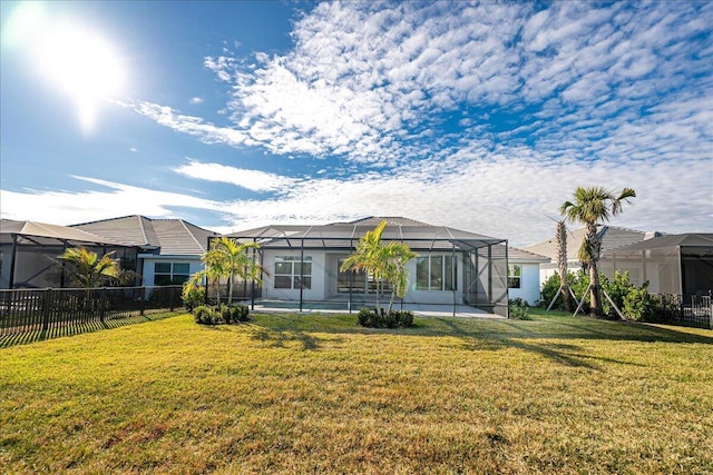 rear view of house with glass enclosure, a patio area, fence, and a lawn