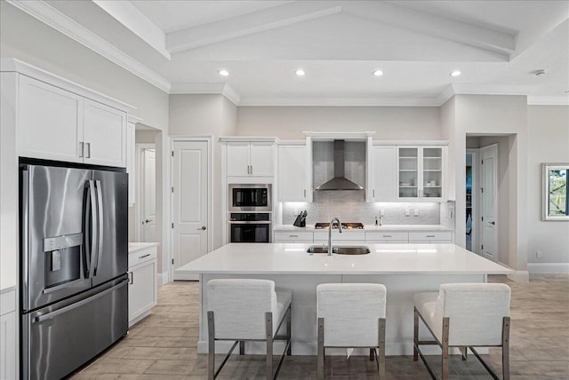 kitchen featuring a breakfast bar, a sink, appliances with stainless steel finishes, wall chimney exhaust hood, and backsplash