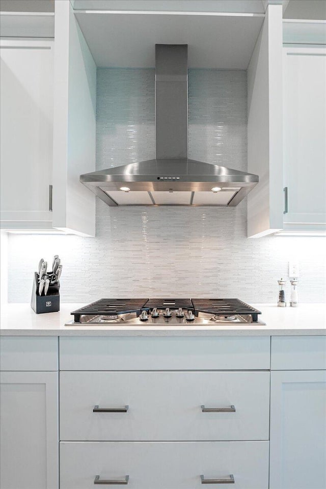 kitchen featuring white cabinetry, wall chimney range hood, and tasteful backsplash