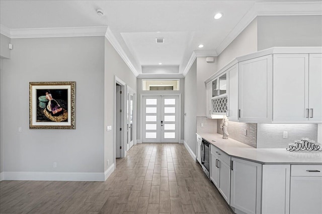 foyer with wood finished floors, baseboards, recessed lighting, ornamental molding, and french doors