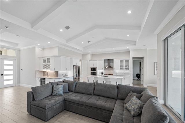 living area with visible vents, beam ceiling, high vaulted ceiling, and baseboards