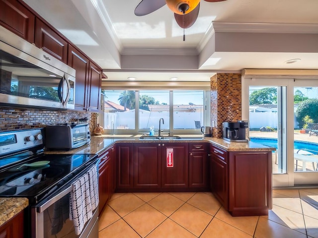 kitchen featuring tasteful backsplash, dark stone counters, stainless steel appliances, sink, and light tile patterned floors