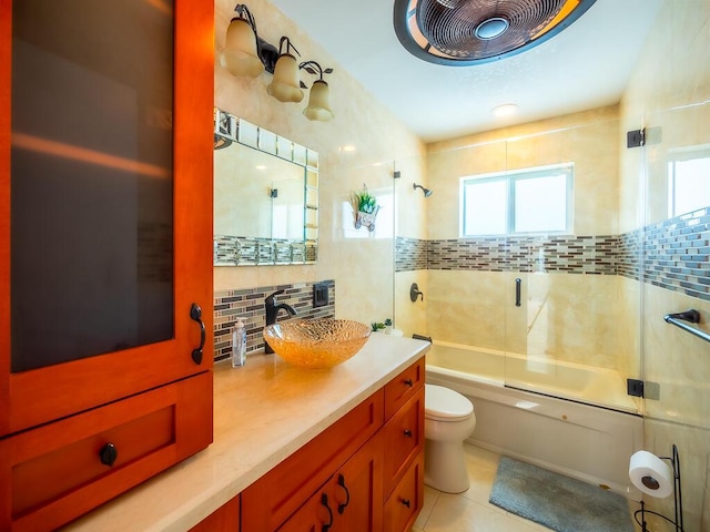 full bathroom with shower / bath combination with glass door, tile patterned floors, toilet, tile walls, and tasteful backsplash