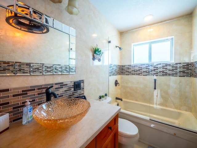 full bathroom featuring vanity, toilet, combined bath / shower with glass door, and tasteful backsplash