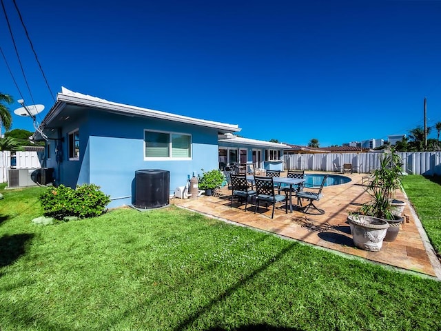 rear view of property featuring a yard, a fenced in pool, and a patio