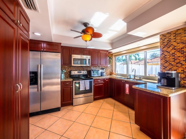 kitchen with light stone countertops, appliances with stainless steel finishes, tasteful backsplash, ceiling fan, and sink