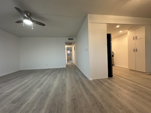 empty room with lofted ceiling, ceiling fan, light hardwood / wood-style flooring, and a textured ceiling