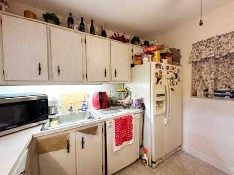 kitchen with white appliances, sink, and light tile patterned floors