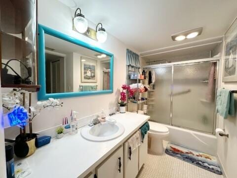 full bathroom featuring combined bath / shower with glass door, tile patterned floors, vanity, and toilet