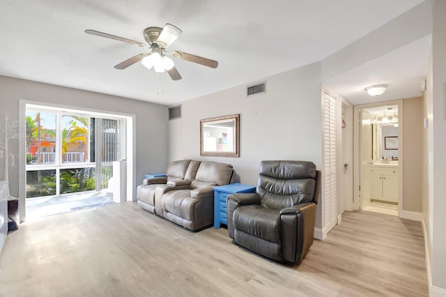 living room featuring light wood-type flooring, ceiling fan, and sink