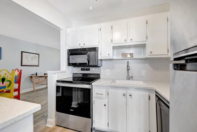 kitchen with light wood-type flooring, tasteful backsplash, sink, black appliances, and white cabinets