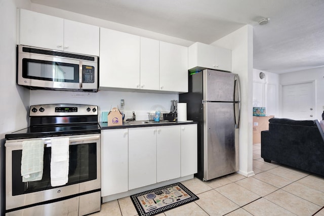 kitchen featuring appliances with stainless steel finishes, light tile patterned floors, and white cabinetry