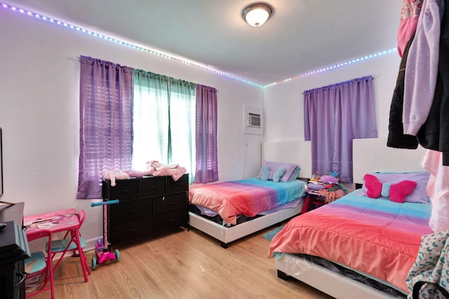 bedroom featuring light wood-type flooring and an AC wall unit