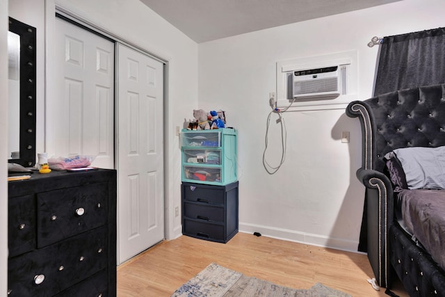 bedroom featuring light hardwood / wood-style floors, a wall unit AC, and a closet