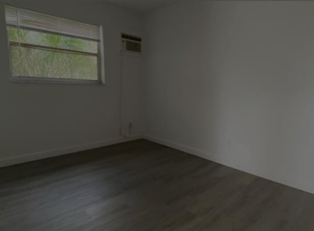 spare room featuring dark wood-type flooring and a wall mounted AC