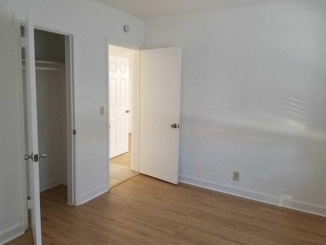 unfurnished bedroom with light hardwood / wood-style flooring and a closet