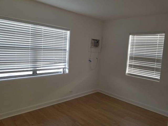 unfurnished room featuring an AC wall unit and hardwood / wood-style floors